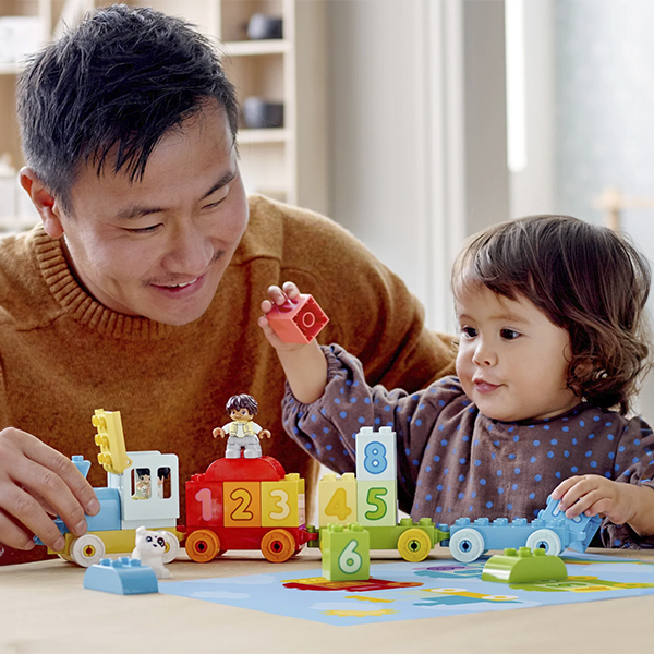 Padre e hijo jugando con LEGO en casa.